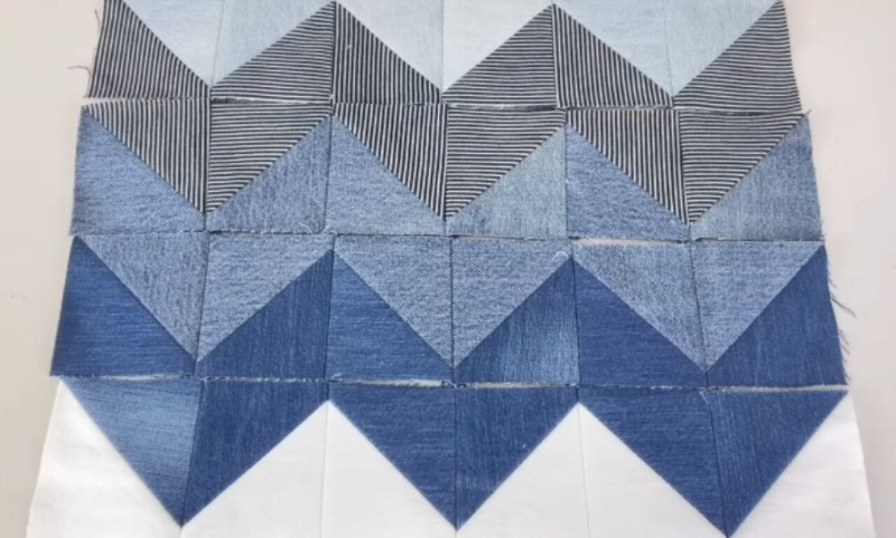 fabric featuring a geometric pattern with various shades of blue and white. The design includes zigzagging triangles and striped sections, creating a visually appealing and intricate design.