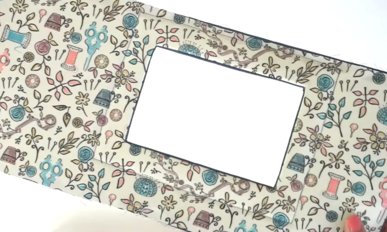 a handmade sewing machine cover with a rectangular cutout in the center.