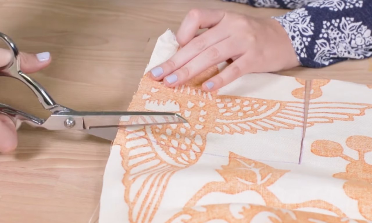 a person using large fabric scissors to cut a piece of cream-colored fabric with an orange floral and bird pattern.a person using large fabric scissors to cut a piece of cream-colored fabric with an orange floral and bird pattern.a person using large fabric scissors to cut a piece of cream-colored fabric with an orange floral and bird pattern.a person using large fabric scissors to cut a piece of cream-colored fabric with an orange floral and bird pattern.a person using large fabric scissors to cut a piece of cream-colored fabric with an orange floral and bird pattern.a person using large fabric scissors to cut a piece of cream-colored fabric with an orange floral and bird pattern.a person using large fabric scissors to cut a piece of cream-colored fabric with an orange floral and bird pattern.a person using large fabric scissors to cut a piece of cream-colored fabric with an orange floral and bird pattern.a person using large fabric scissors to cut a piece of cream-colored fabric with an orange floral and bird pattern.a person using large fabric scissors to cut a piece of cream-colored fabric with an orange floral and bird pattern.