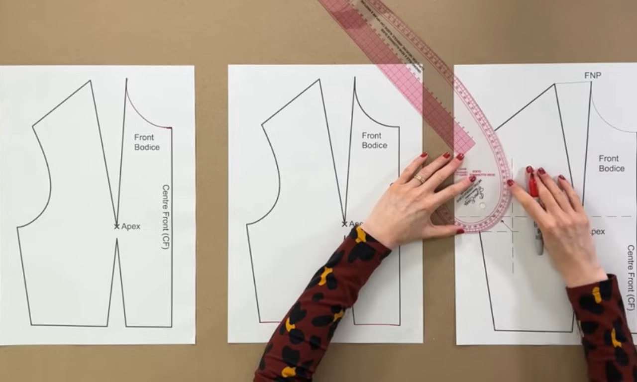 a person working on a sewing or pattern-making project. The individual is using a curved ruler and a pencil to adjust or trace a pattern on paper. The pattern pieces are labeled with terms such as "Front Bodice," "Apex," and "Centre Front (CF)." The person is carefully aligning the ruler to create or modify the curves on the pattern, likely for garment construction. The scene is set on a flat surface, possibly a table, with the pattern pieces laid out for easy access and modification.