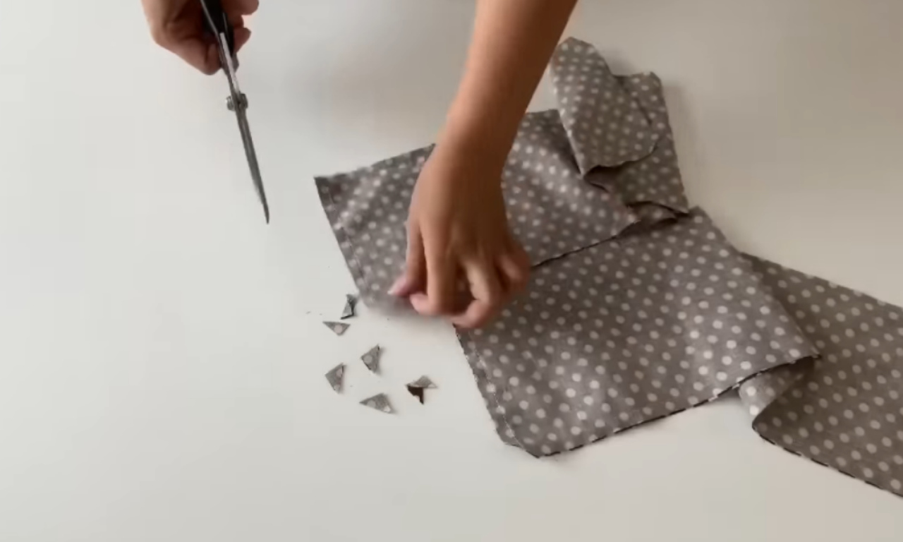 hands sewing a dark blue fabric organizer with multiple pockets.