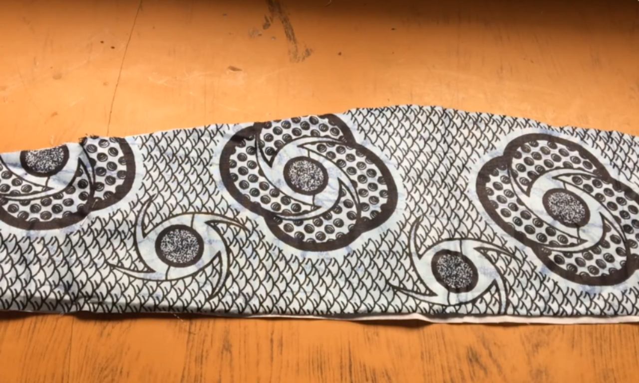 A strip of black and white patterned fabric with swirling designs on a wooden surface.