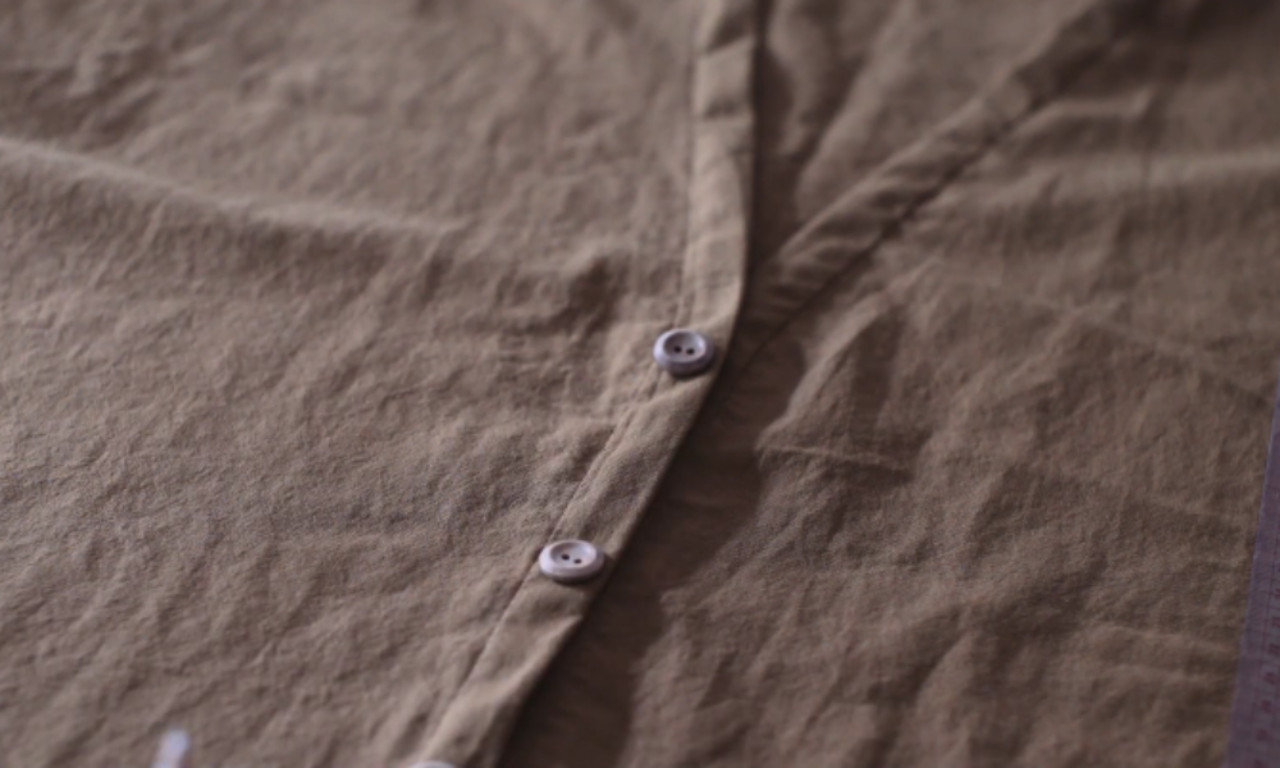 Close-up of textured brown fabric featuring a button placket with light-colored buttons.