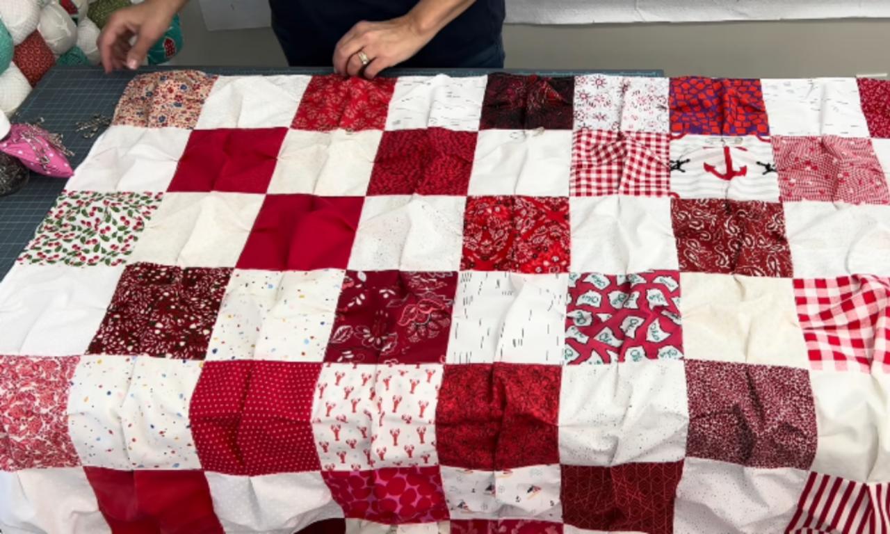 The red and white puff quilt top, with pleats sewn along the seams of each square, laid out on a cutting mat before stuffing.