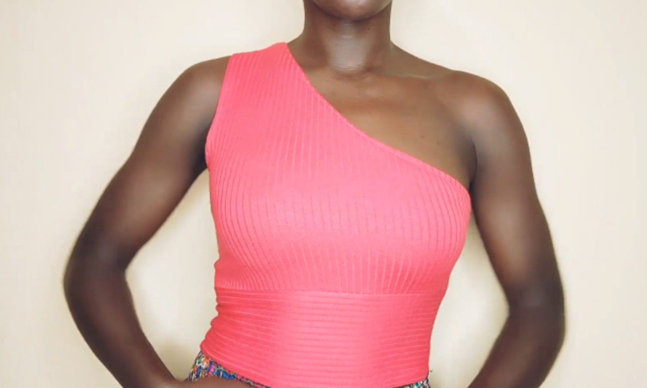 A model showing the final result of the DIY tutorial, wearing a stylish and perfectly fitted pink ribbed one-shoulder top.