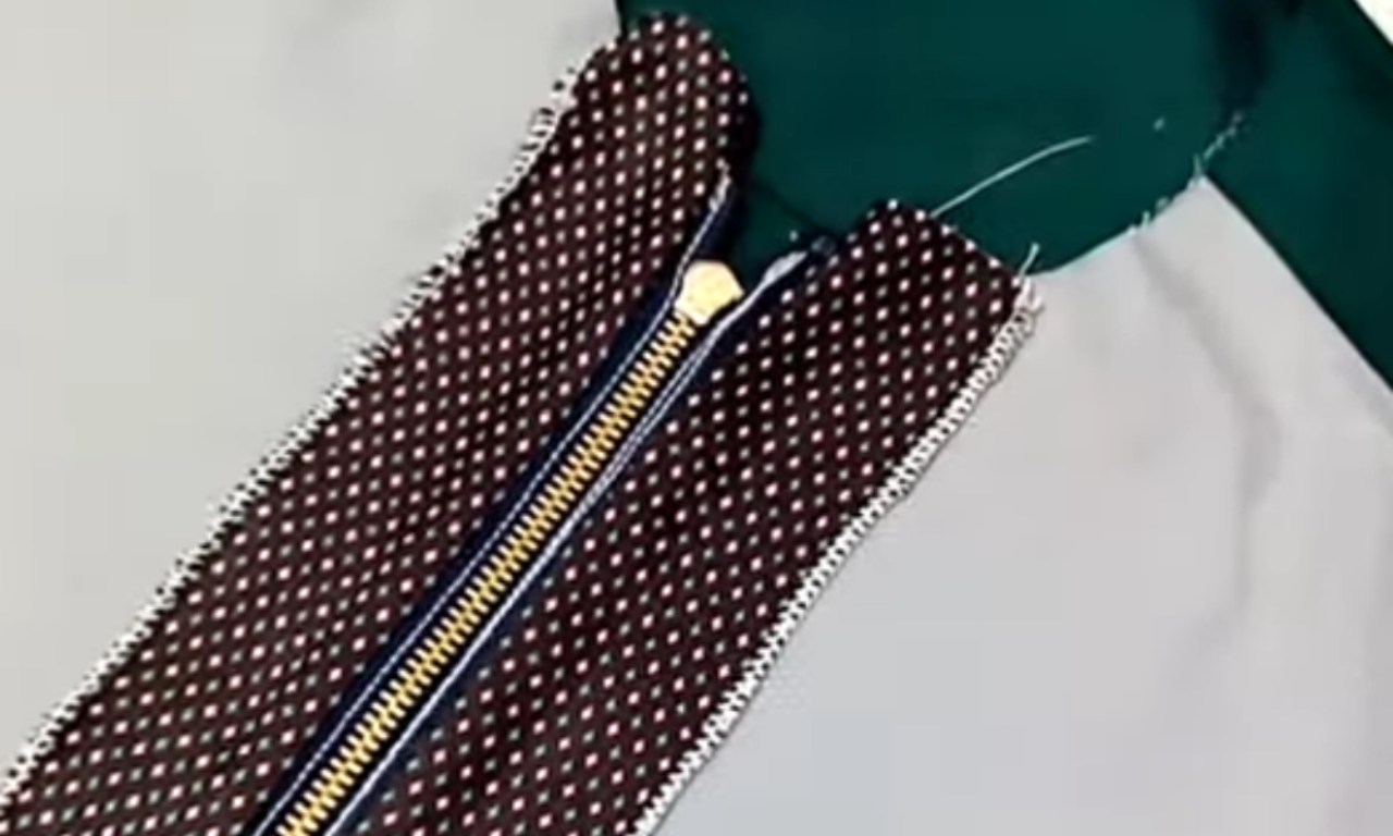 The inside of a garment, showing a zipper cleanly installed with a brown and white polka-dot facing that neatly covers the zipper tape.