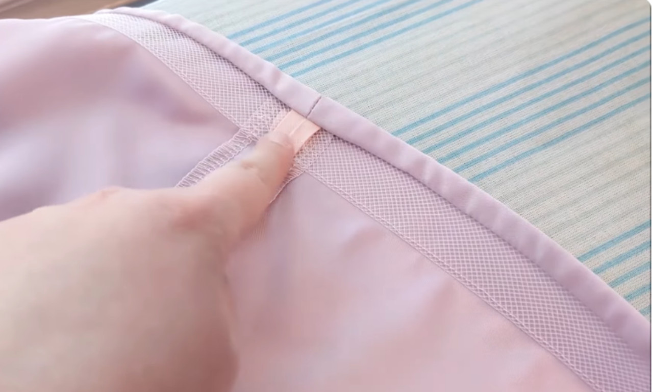 A finger points to the finished seam on the inside of a light purple hem, showing how the ends of the horsehair braid are neatly overlapped and covered with soft bias tape.