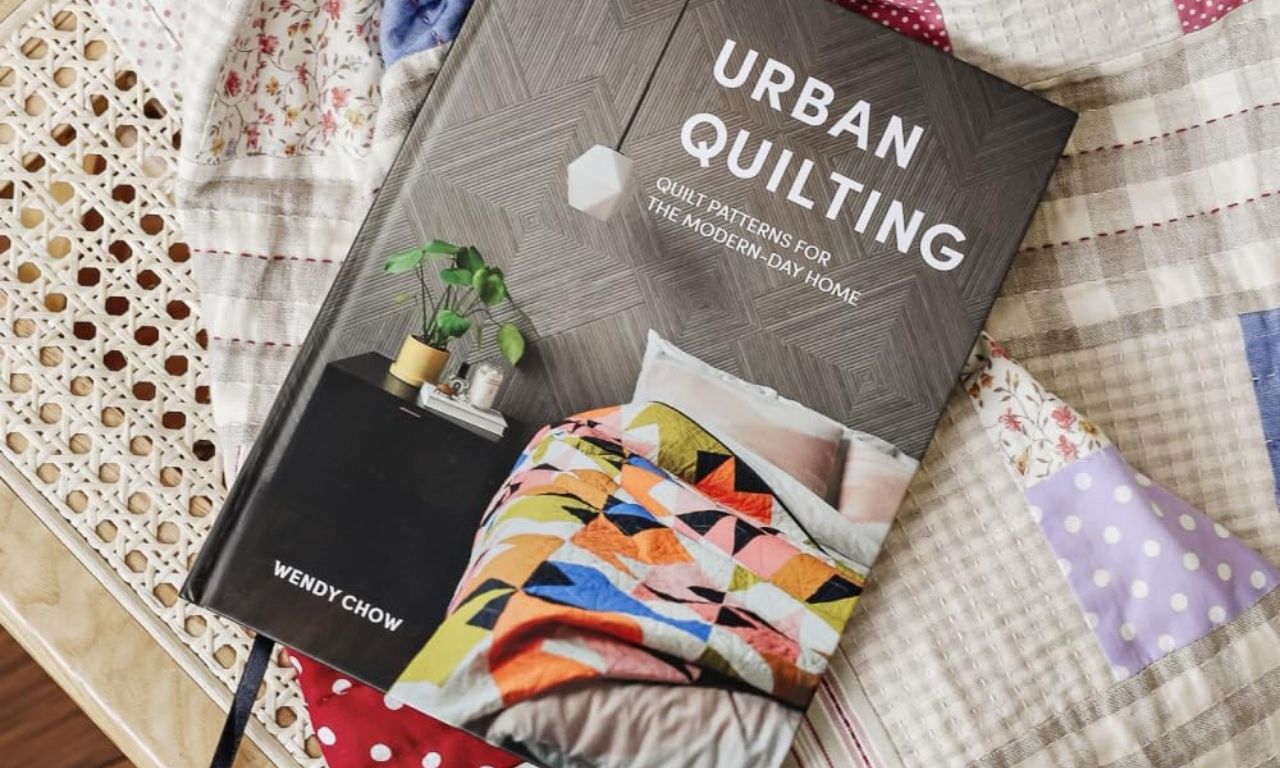 A collection of quilting books neatly arranged on a table, featuring colorful covers and sewing patterns for quilters of all skill levels.