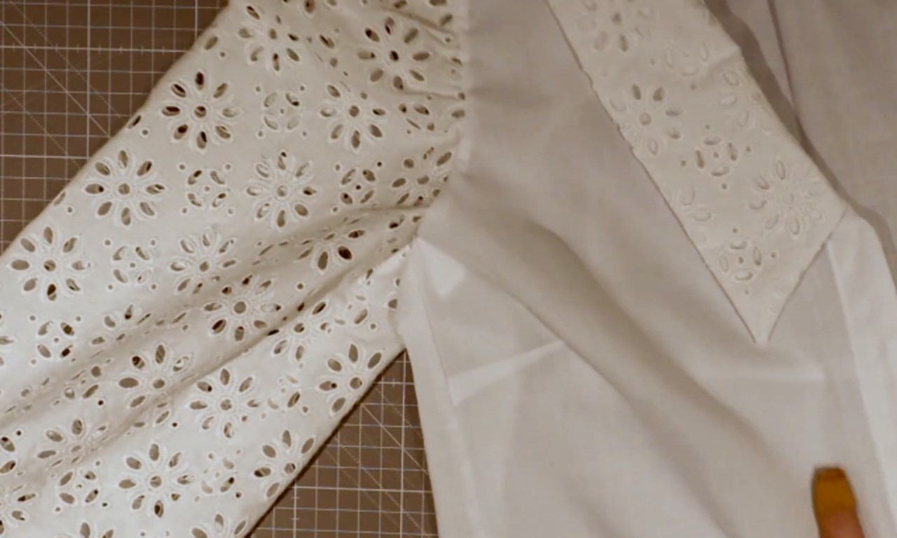 A finished French seam attaching a white eyelet lace sleeve to the bodice of a blouse, showing a clean finish perfect for delicate fabrics.