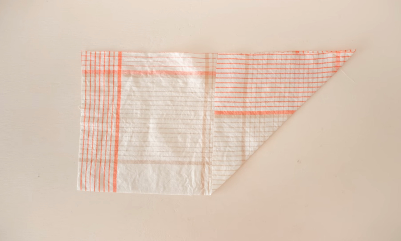 A piece of light-colored plaid fabric, folded diagonally, showing the material used for the gathered bodice project.