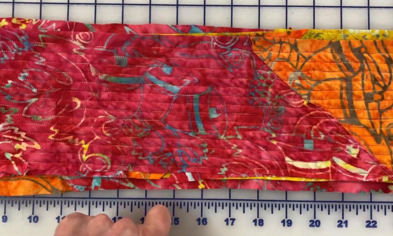 A close-up of the chenille scarf fabric after sewing parallel lines of stitches down its entire length, holding the layers together.