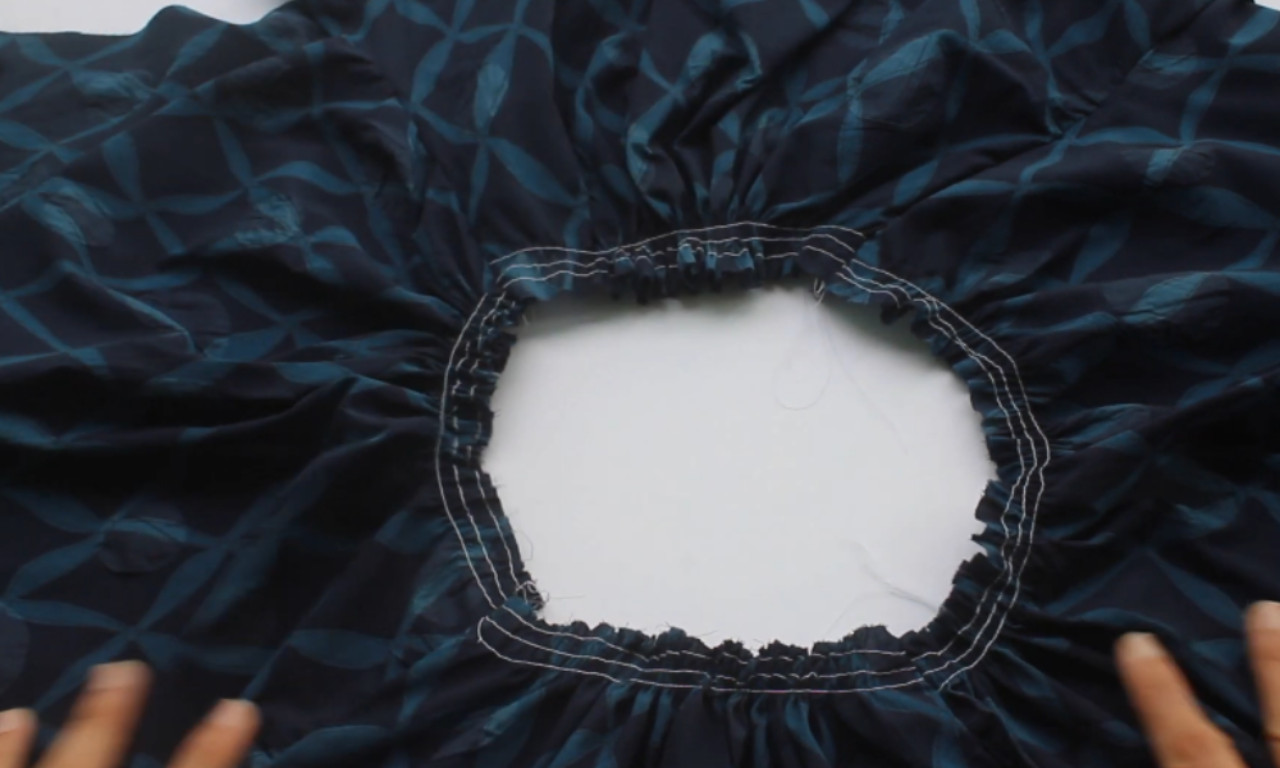 The inside of a dark blue peasant blouse showing the gathered neckline with elastic stitched into a casing.