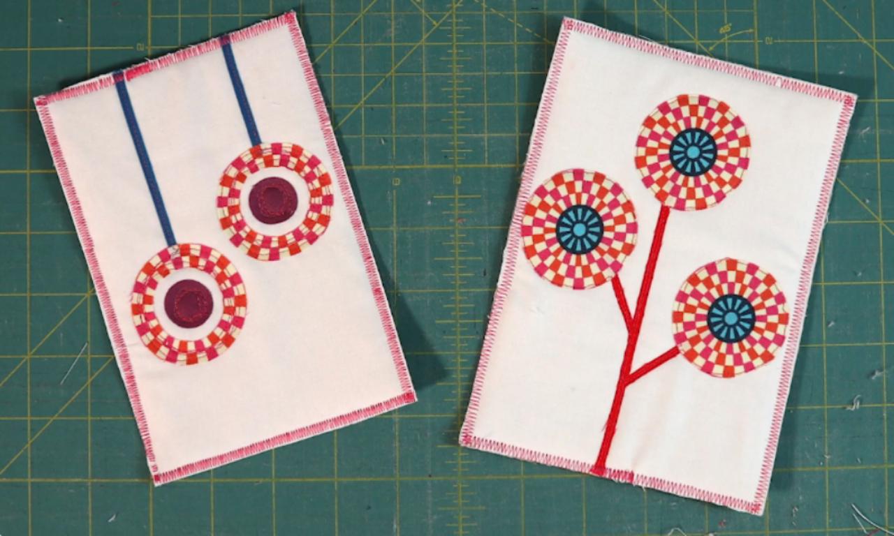 A collection of two fabric appliqué designs featuring circular patterns in red, pink, and blue. The left piece shows two hanging circular designs with blue lines, while the right piece displays a tree-like structure with three colorful circular flowers at the ends of red stems. Both are stitched with a pink zigzag border.