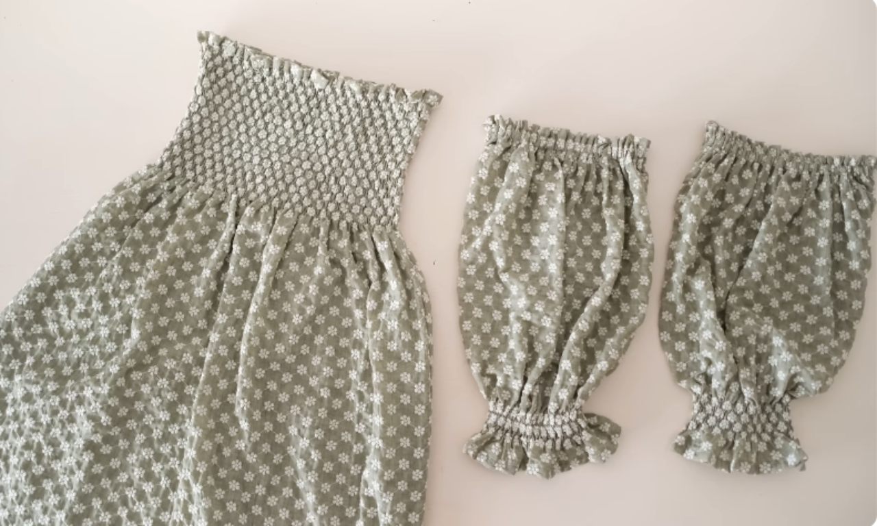 The dress laid flat next to two separate shirred puff sleeves, demonstrating the detachable sleeve option.