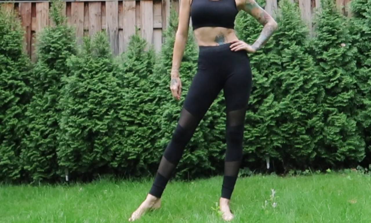 A woman stands in a garden modeling her finished black DIY mesh leggings, showing the sheer panels on the thighs.