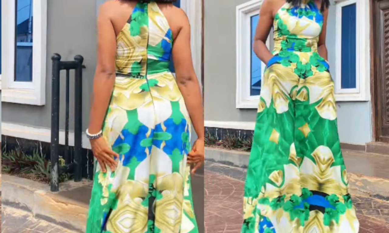 A woman modeling a vibrant halter-neck palazzo jumpsuit with a green, blue, yellow, and cream abstract floral pattern. The front and back views are shown outdoors in front of a modern building.