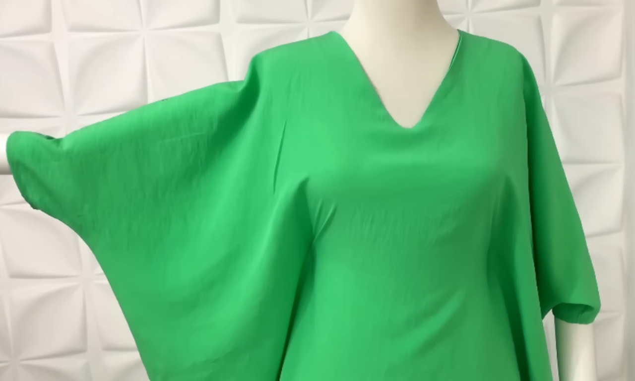 A bright green caftan dress, the finished result of the sewing tutorial, is displayed on a mannequin to show its V-neck and wide, flowing shape.