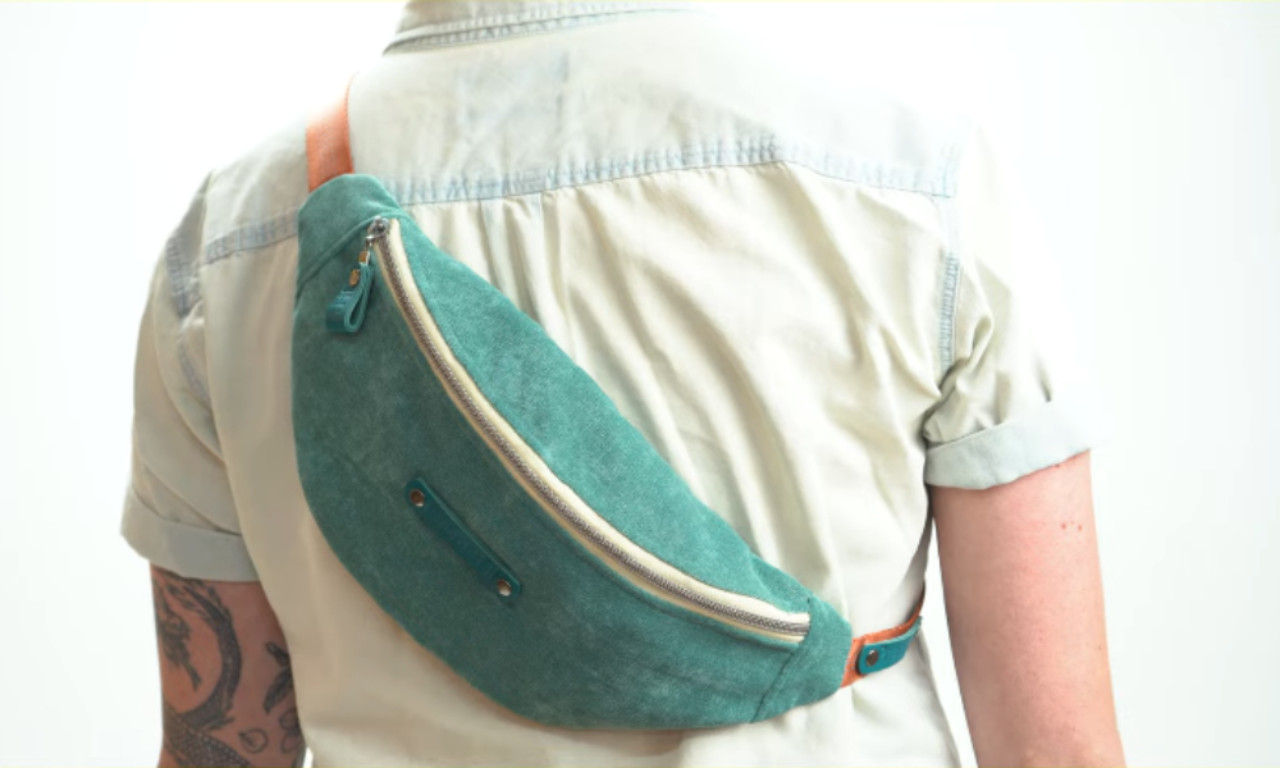 A person wearing a finished teal fanny pack slung crossbody over their back, showing a stylish way to wear the bag.