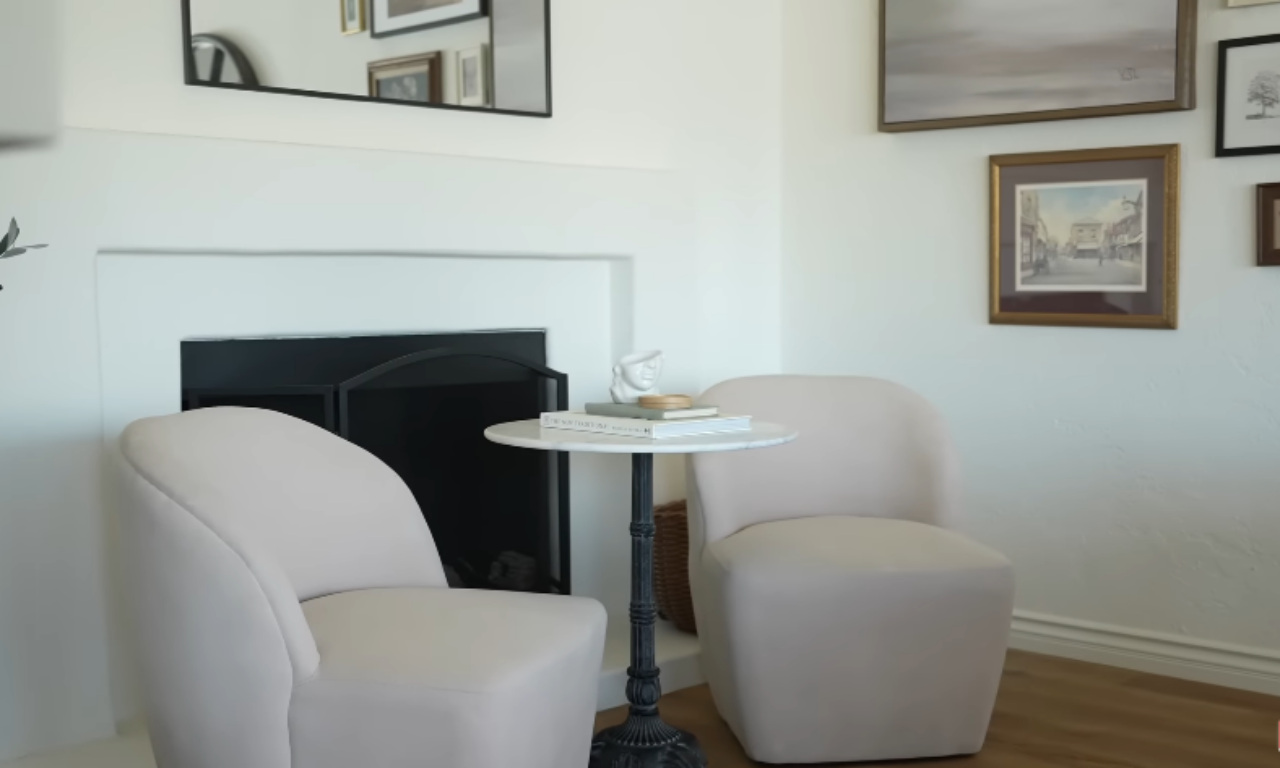 A cozy white living room corner showing floor-to-ceiling decorating with a gallery wall, a floor lamp, and a low-profile plant