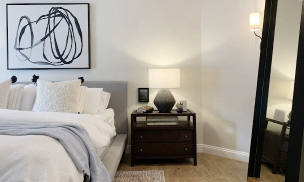 A bedroom corner with a large black-and-white abstract artwork hung above the bed, demonstrating the one-large-piece strategy