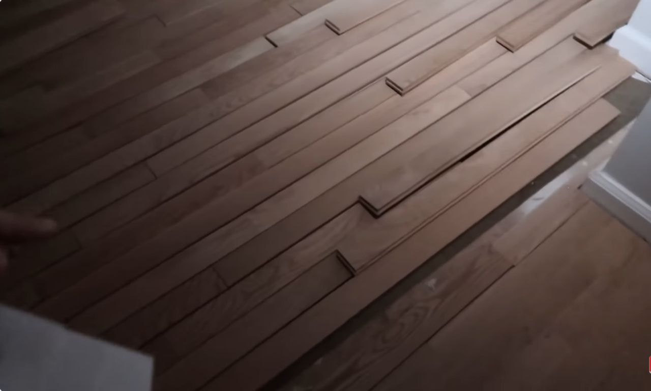 Hardwood flooring planks partially laid over an existing, darker wood floor, showing the process of installation or repair before finishing.