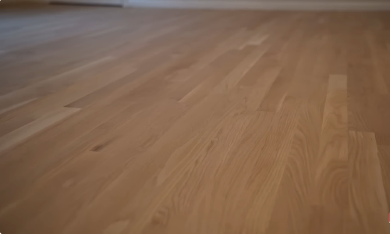 Close-up view of newly sanded and refinished natural-toned hardwood flooring, showing a clean, light wood grain.