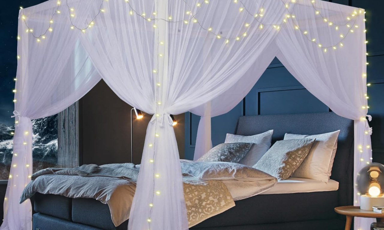 White four-corner post bed canopy curtains made of breathable 380-mesh polyester draped over a king-size bed, featuring decorative fairy string lights and ties for a dreamy, romantic bedroom aesthetic.