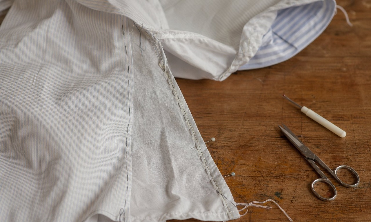 A men's shirt inside out with a basting stitch along the new side seam and pins marking a fitting adjustment at the waist
