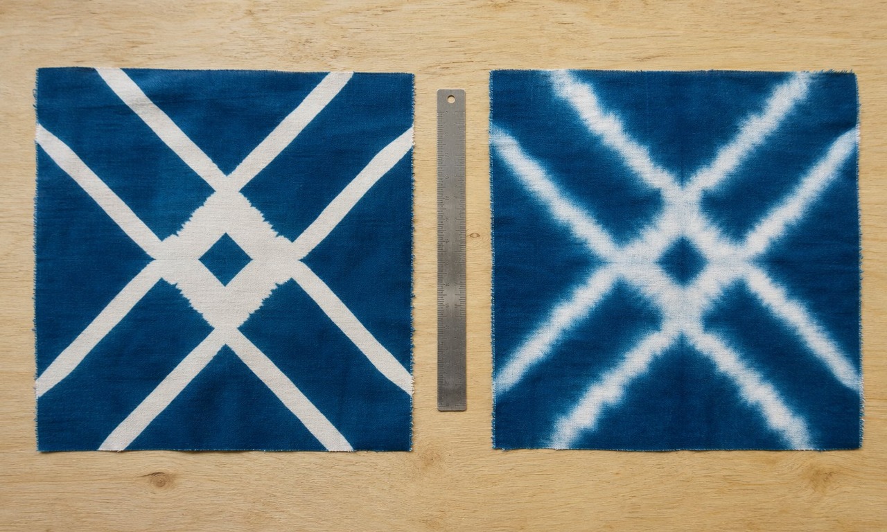 Two pieces of batik cotton side by side, one with crisp pale resist lines and one with blurred edges where dye has crept under the resist