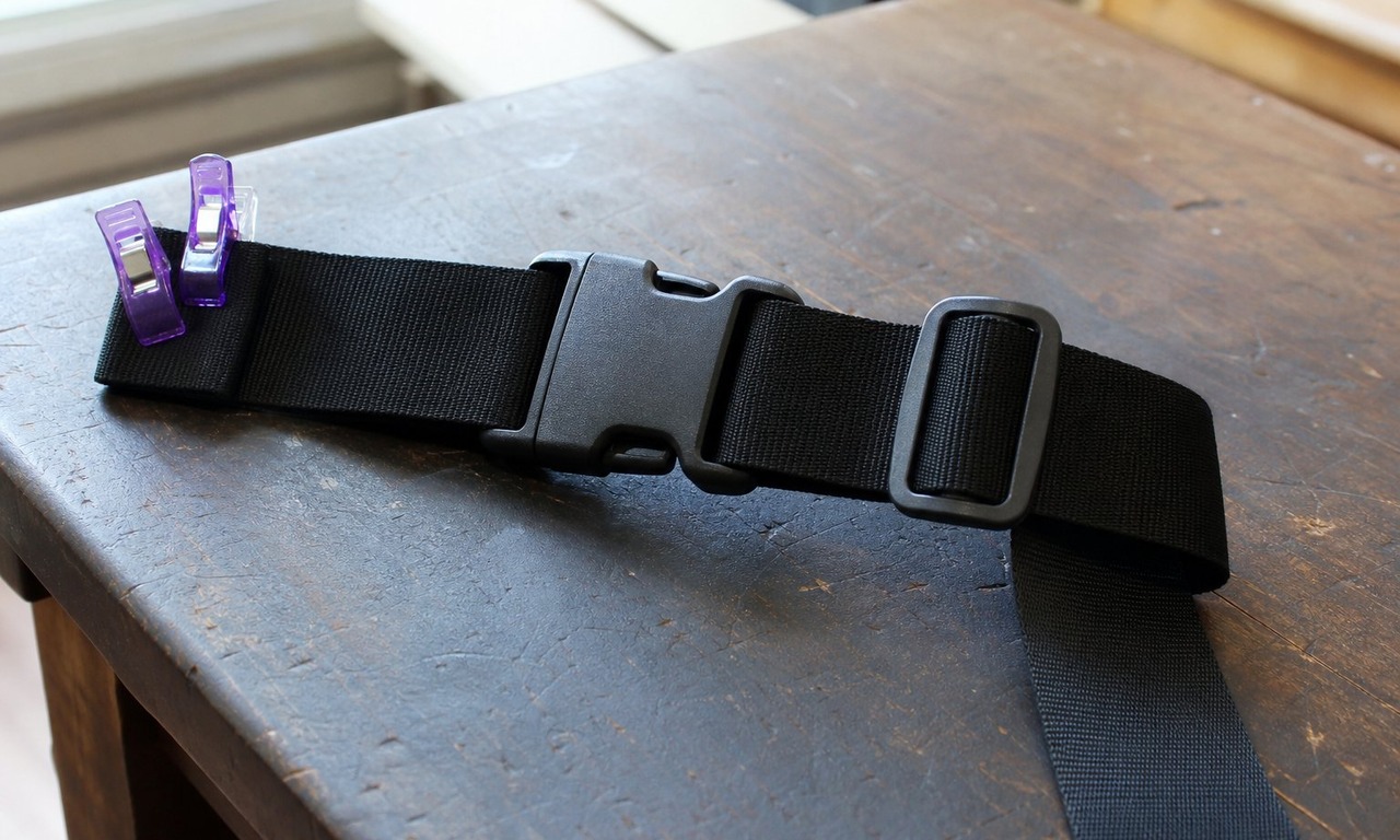 Black webbing threaded through a side release buckle and a tri-glide slider on a workbench